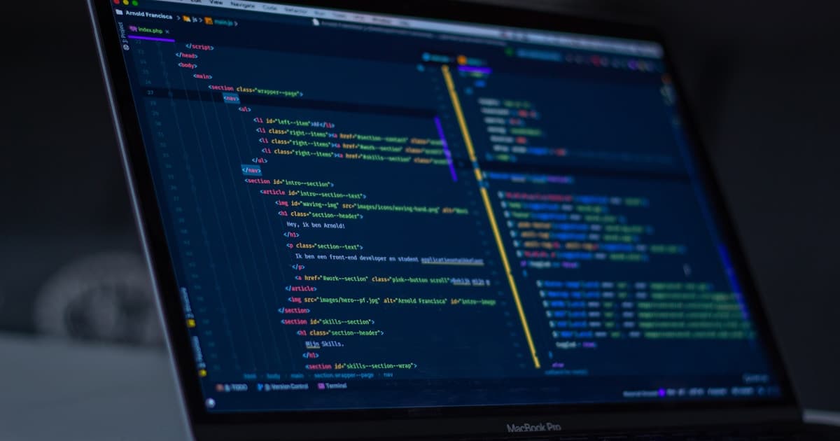 A developer writes Python code on a laptop screen in a modern engineering workspace