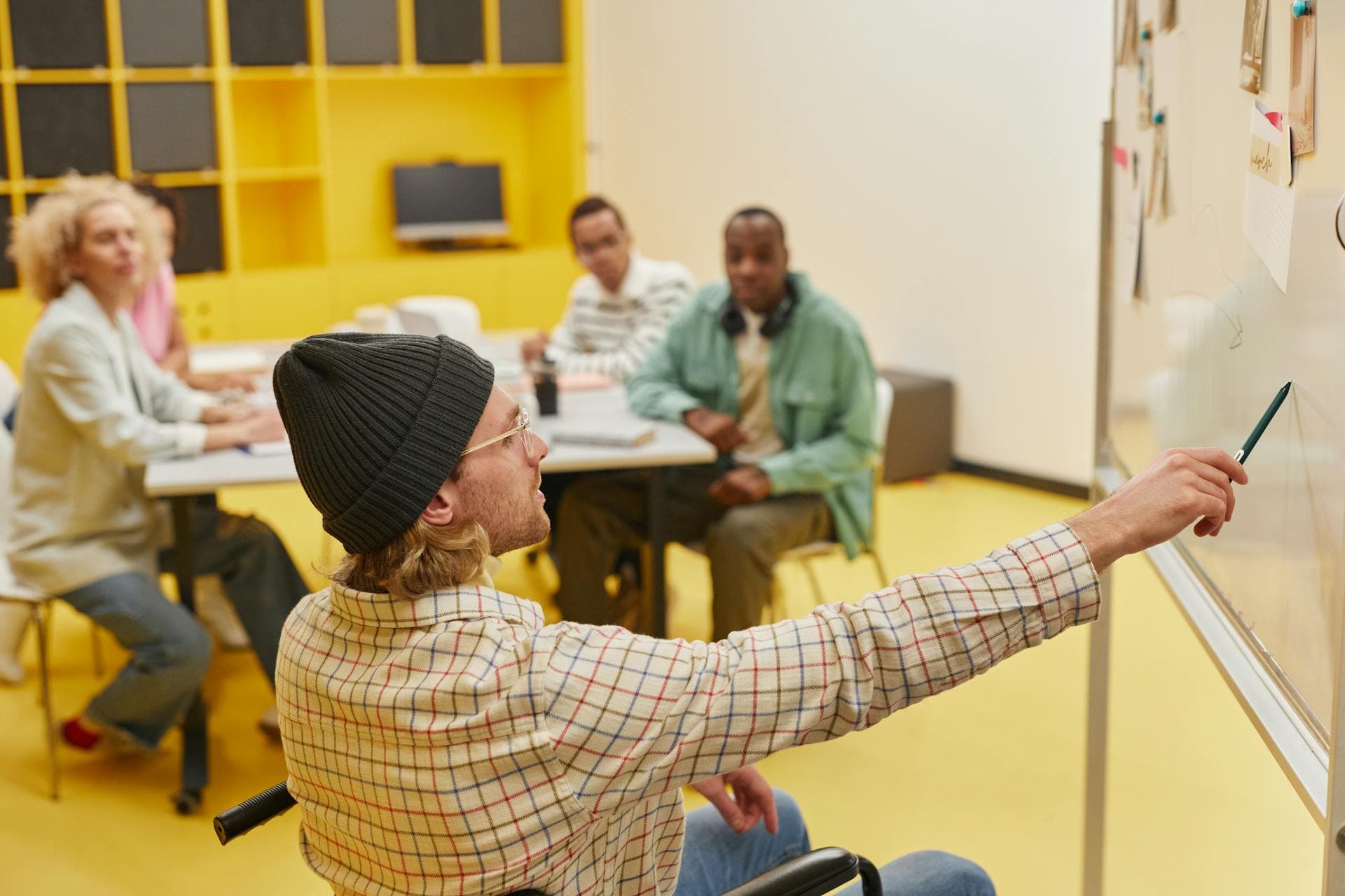 A manager explaining work in front of a whiteboard, representing the communication and calibration expected in Engineering Manager interviews