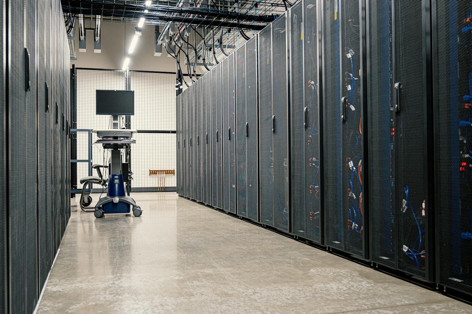 A wide view of server racks, network cables, and infrastructure cabinets in a modern data center