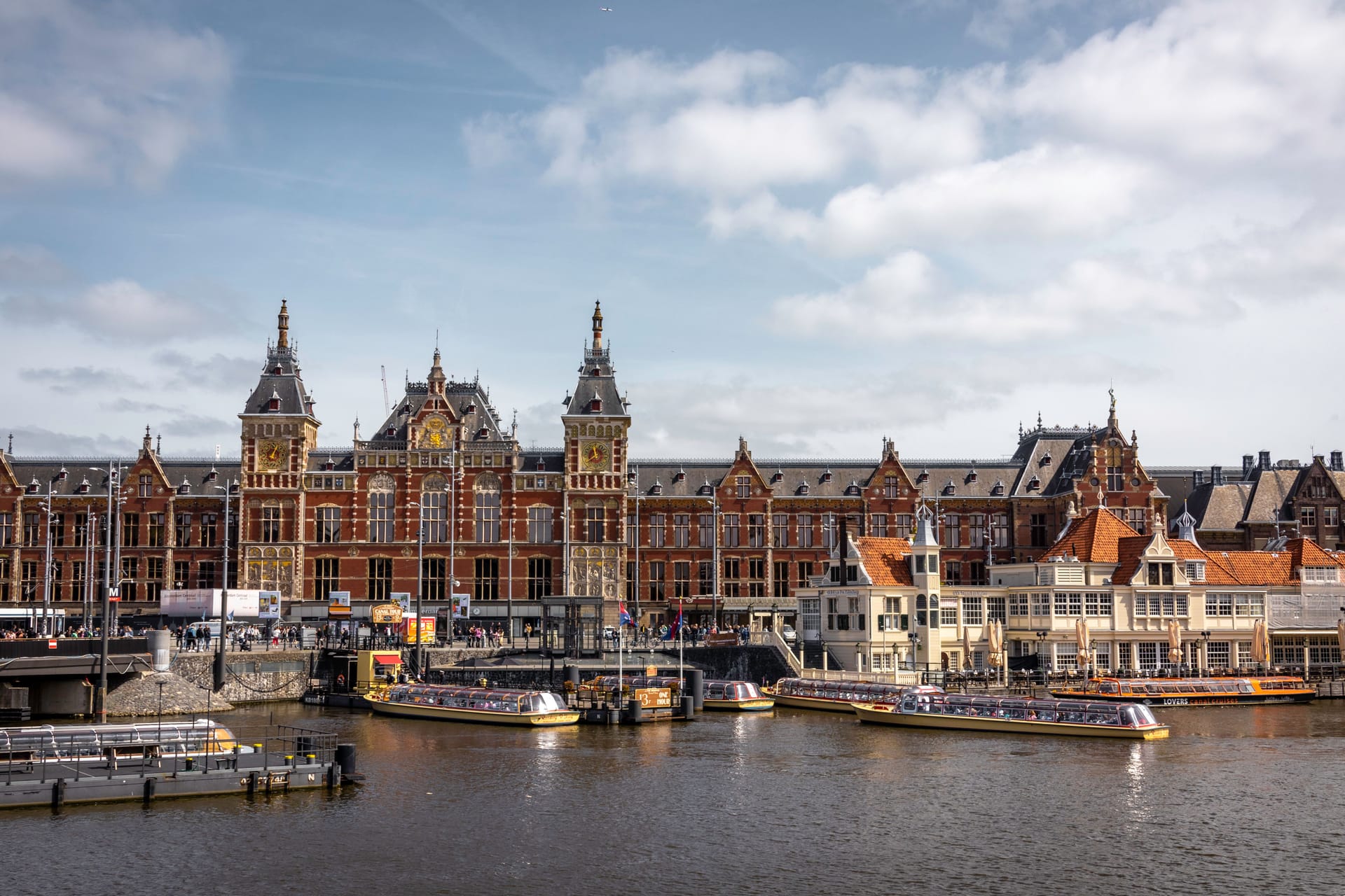 Amsterdam Centraal Station waterfront with water buses and city architecture, showing the transit access that supports Amsterdam's tech commute patterns.