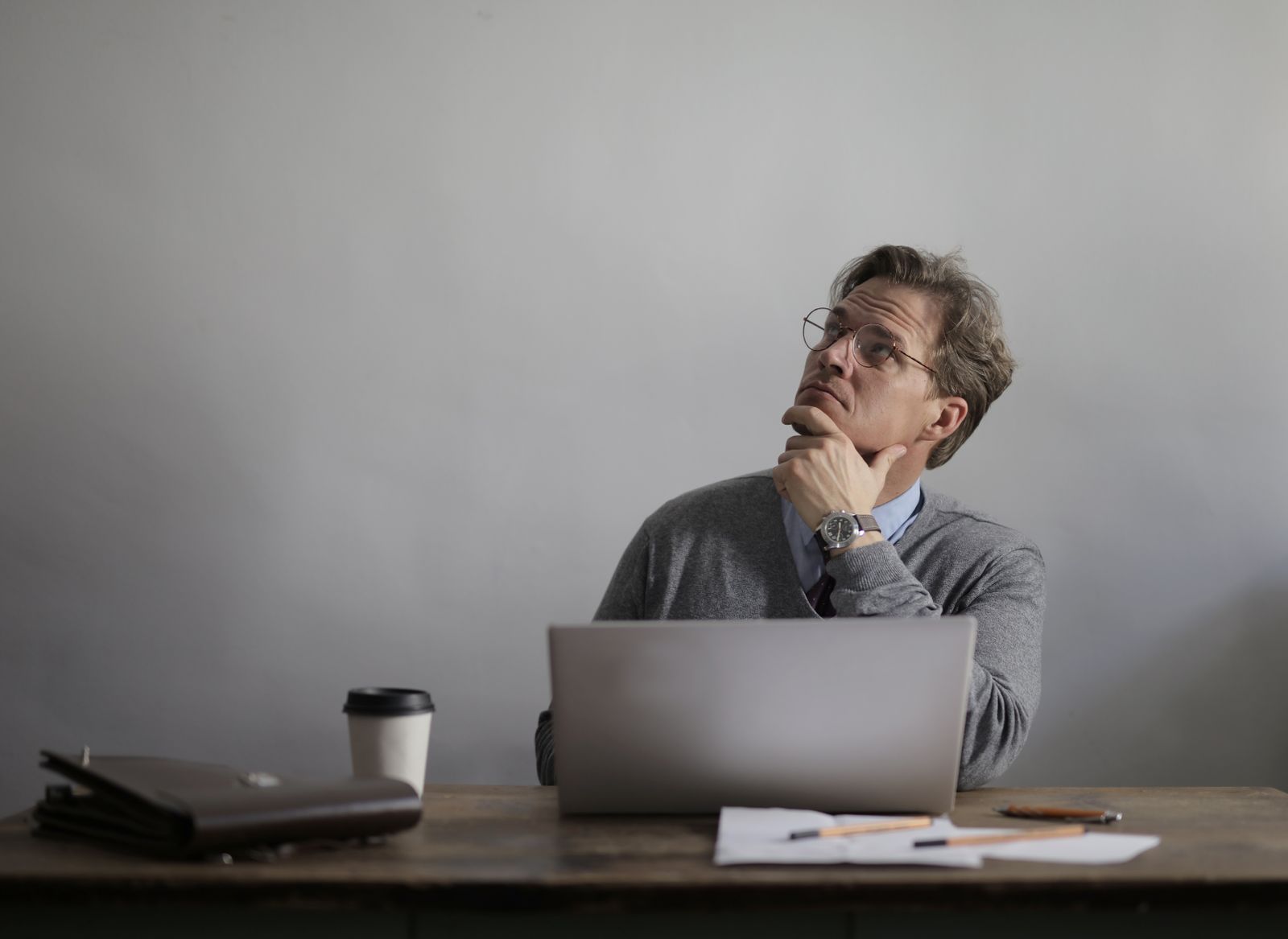A man considering his next steps at a desk with a laptop and notes.