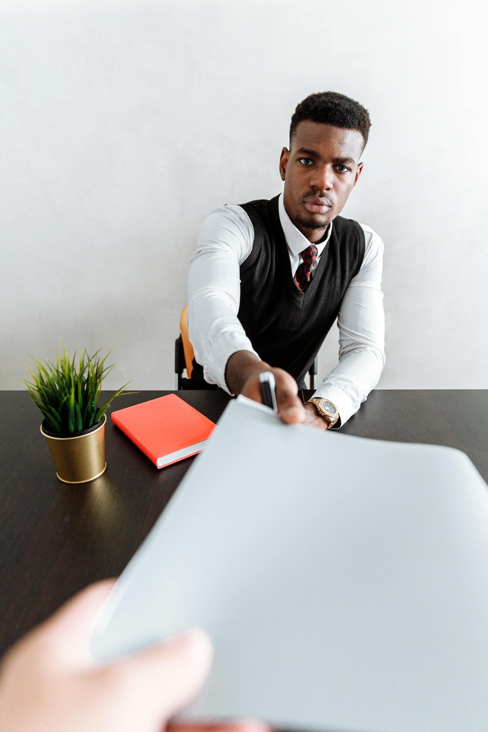 A professional handing a document across a desk, representing the direct application and human review process that happens after leaving crowded job boards.