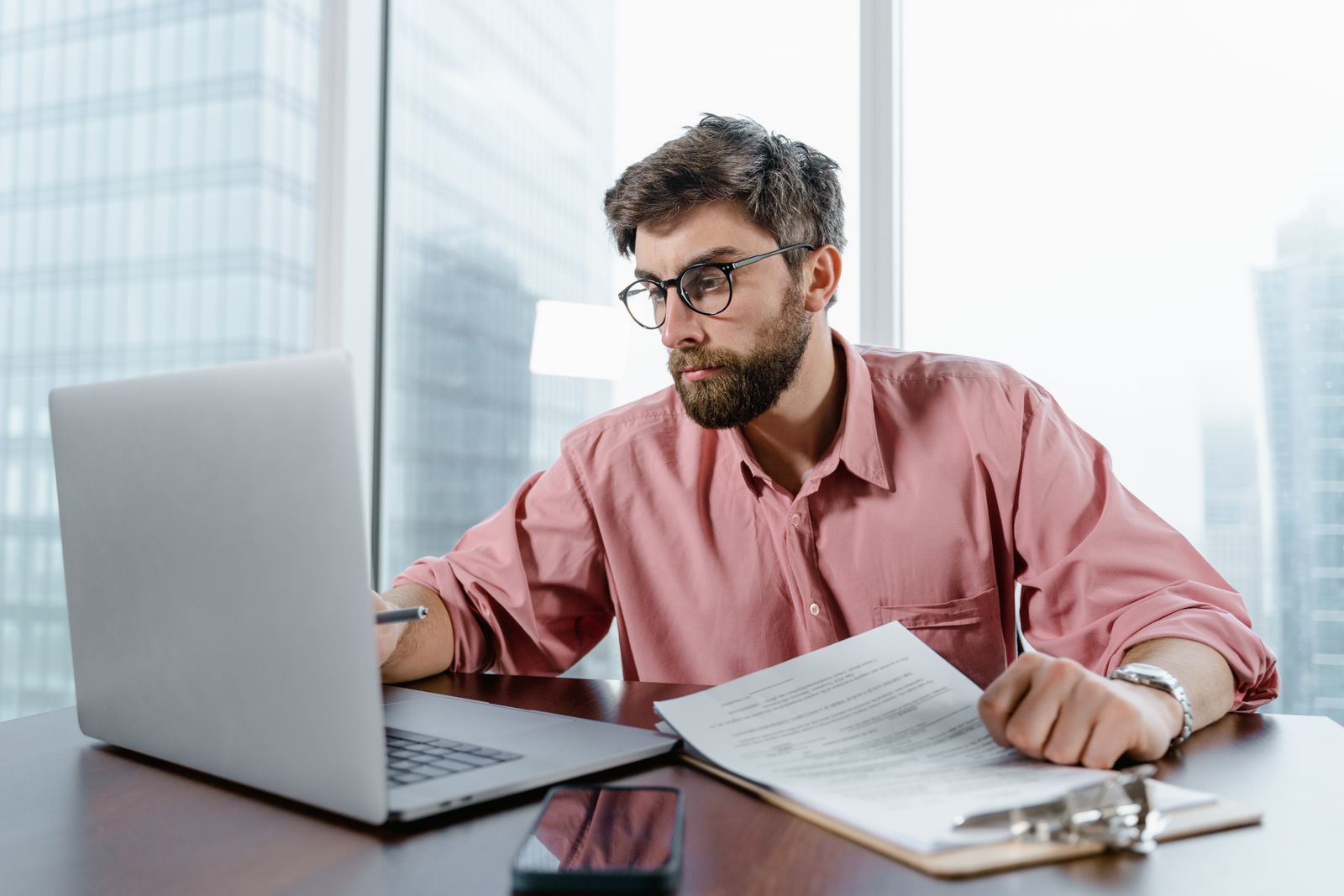 A professional reviewing documents beside a laptop, representing the recruiter scan that decides whether a resume receives deeper review.