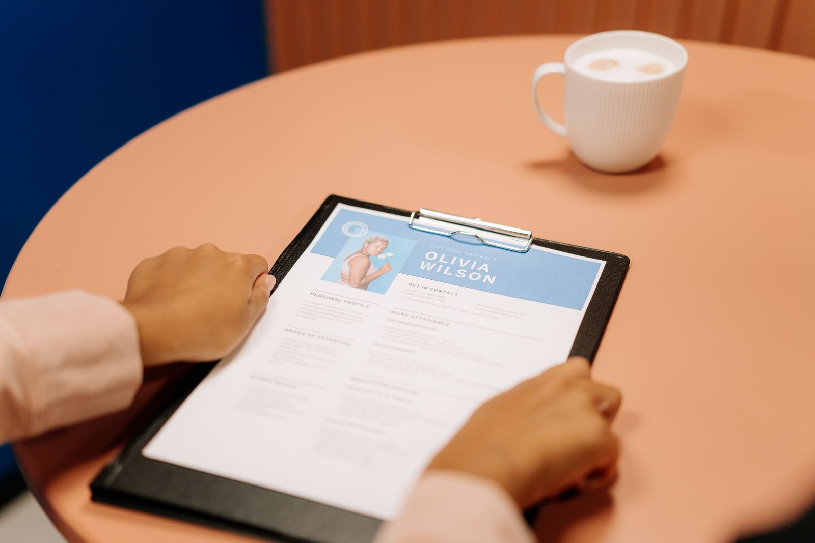 A person reviewing a resume on a tablet at a coffee table, representing the keyword extraction workflow that pairs resumes with job description requirements.